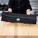 A woman holding a black Mercer Culinary knife case on a wooden table.