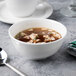 A bowl of soup with a spoon in a white bone china bowl.