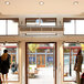 A Schwank surface mounted air curtain over a door in a store with people walking in.