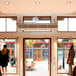 A Schwank surface mounted air curtain above a store entrance with a couple of people in front of it.