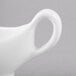 A close-up of a white Reserve by Libbey sauce boat with a handle.