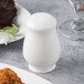 A Reserve by Libbey bone china salt shaker on a table with food.