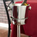 A silver Vollrath wine bucket stand holding a wine bottle.