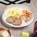 A clear Cambro plate cover on a plate with food inside on a table.