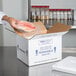 A person holding a fish in a Polar Tech insulated shipping box.