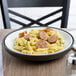 A Dinex insulated meal delivery base with a plate of pasta with sausages and pesto sauce.