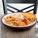 A plate of pasta with bread on an insulated Dinex meal delivery base.