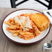 A plate of Dinex cranberry pasta with cheese and bread on a table.