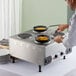 A man cooking food on a Nemco countertop raised hot plate with solid burners.