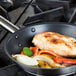 A Vollrath Optio non-stick fry pan with food cooking on a stove.