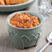 A bowl of chili on a table with a spoon.