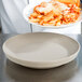 A chef using a Dinex Latte insulated meal delivery base to serve a plate of pasta with bread.