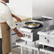 A man cooking food on a Cooking Performance Group countertop range with a pot on one burner.