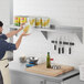 A man in a blue shirt and apron using a Regency stainless steel wall shelf to hold a can of corn.