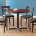 A black table with a Lancaster Table & Seating cast iron table base plate with chairs around it.