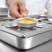 A person using a Vollrath 15 hole plate to pour egg into a bowl.