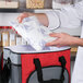 A person holding a Nordic gel cold pack in a red and grey cooler bag.