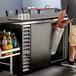 A man holding a keg in a Beverage-Air back bar refrigerator.
