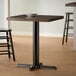 A Lancaster Table & Seating cast iron table base plate on a table in a restaurant dining area.