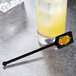 A black rectangular stirrer in a drink with ice cubes.