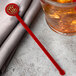 A glass of tea with a red WNA Comet disc stirrer in it.