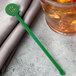 A glass of brown liquid with a green WNA Comet Spirit disc stirrer in it.