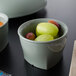 A white Cambro insulated plastic bowl filled with green grapes on a black surface with a white stripe.