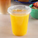 A plastic cup of orange juice with a lid.