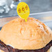 A hamburger with a yellow plastic oval pick in it.