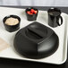 A black plastic tray with a black bowl of oatmeal and strawberries on it.