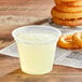 A Fabri-Kal plastic cup of liquid on a table next to a stack of onion rings.