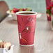 A red Solo paper hot cup with bistro print on a table with a cup of coffee in it.