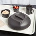 A black plastic tray with a bowl of strawberries and a smoked metal Cambro insulated plastic bowl on it.