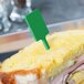 A sandwich with ham and cheese on a plate with a green rectangular pick.
