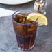 A clear plastic tumbler of iced tea with a lemon wedge