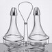 A clear glass Tablecraft oil and vinegar cruet set with metal holder.