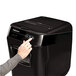 A hand pressing a button on a black Fellowes AutoMax 200C shredder.