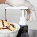 A person using a Carlisle condiment pump to pour chocolate syrup onto a bowl of ice cream.