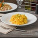 A Libbey white porcelain bowl filled with macaroni and cheese on a table.