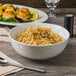 A bowl of noodles with vegetables and greens in a Libbey porcelain noodle bowl.