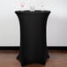 A black Snap Drape spandex table cover on a round table with two wine glasses on it.