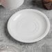 A Libbey white porcelain saucer with two wells on a table.