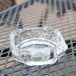 An Anchor Hocking clear glass ashtray sitting on a table.