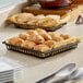 A Clipper Mill black square grid basket of croissants on a counter.