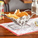 A metal basket with chicken and french fries on a table.