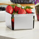 A stainless steel Clipper Mill square berry basket filled with strawberries.