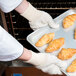 A person using Cordova terry baker gloves to take croissants out of the oven.