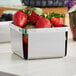 A stainless steel Clipper Mill square berry basket filled with strawberries.