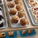 A white fiberglass market tray of muffins on a table in a bakery display.