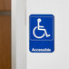 A blue and white Vollrath Traex Handicap Accessible sign with a person in a wheelchair.